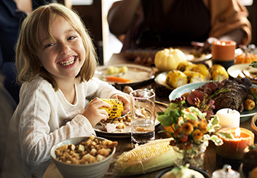 Little girl eating corn during an RMA Thanksgiving celebration