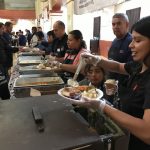 Volunteers serve food to patrons in the buffet line
