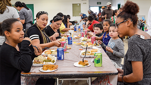 Several families are pictured, eating dinner at Rescue Mission Alliance Central Coast's dining hall