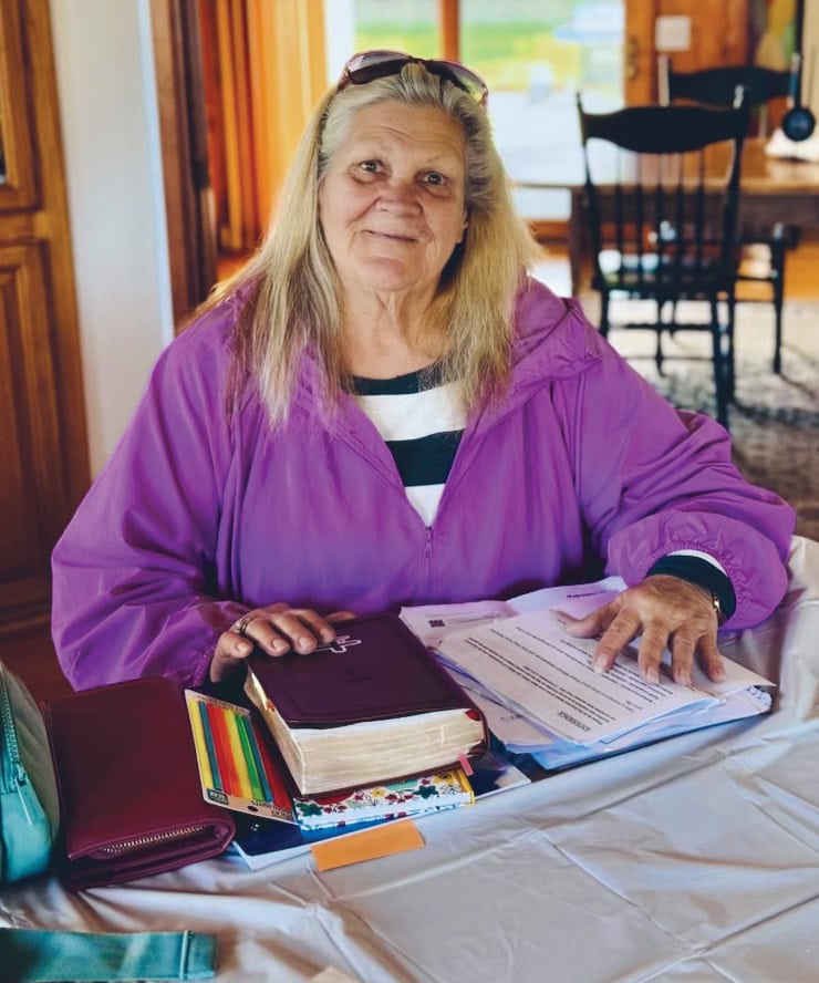 Rescue Mission Alliance Central Coast volunteer woman with documents and books at table.