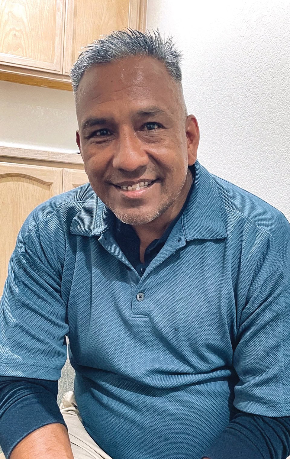 A smiling man in a blue polo shirt at Rescue Mission Alliance Central Coast office.