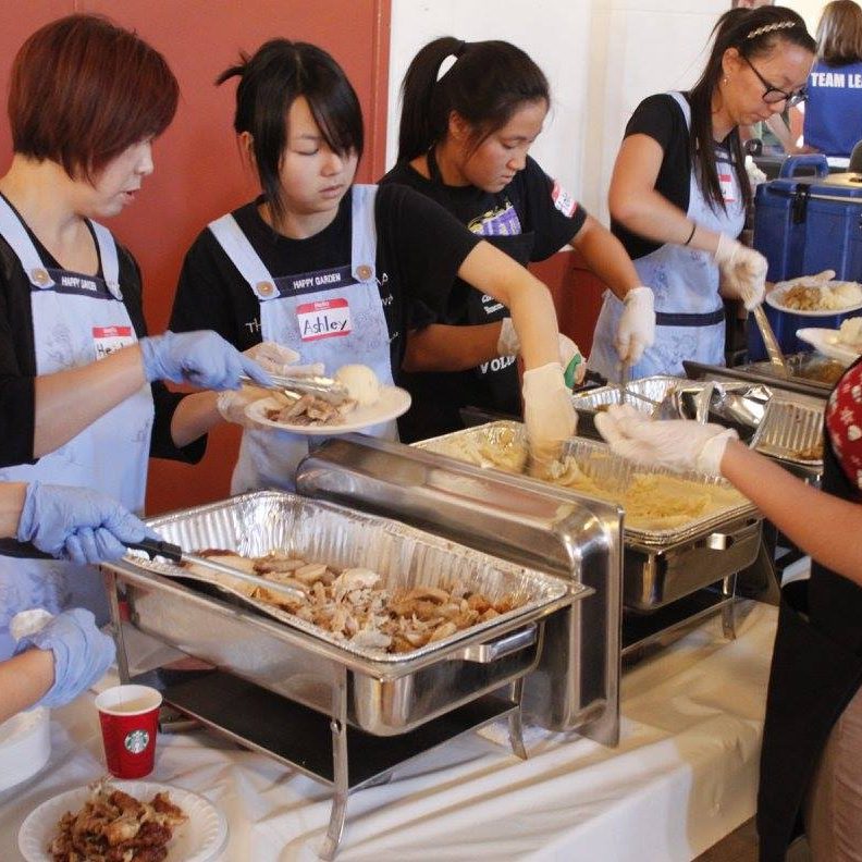 Volunteers serve big portions of mashed potatoes and turkey from hot food pans