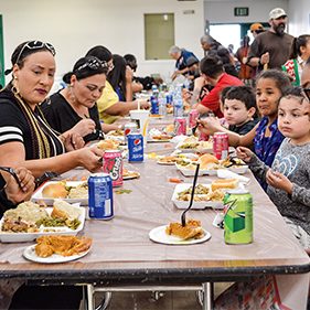 Several families are pictured, eating dinner at Rescue Mission Alliance Central Coast's dining hall
