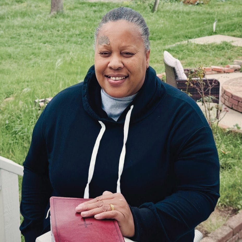 Rescue Mission volunteer smiling outdoors with a Bible in hand on the Central Coast.