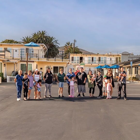Group of people gathered outside residential buildings at Rescue Mission Central Coast.
