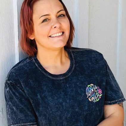 Smiling woman with red hair wearing a Rescue Mission Alliance T-shirt.